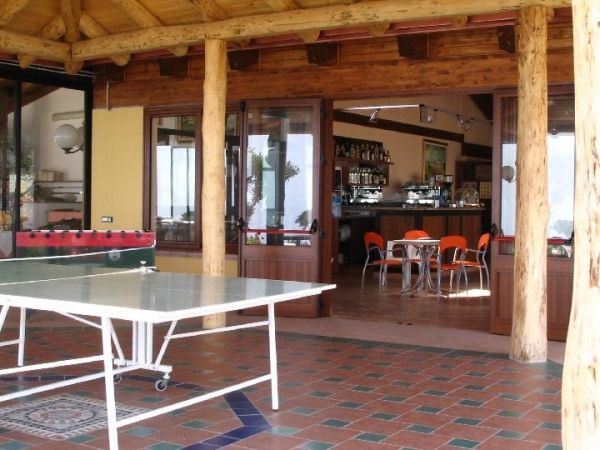 Una veranda con tavolo da ping pong e vista su un bar interno.
