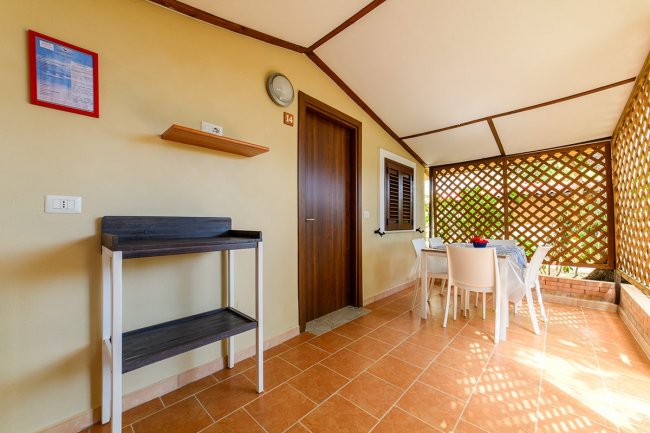 Veranda con tavolo, sedie e scaffale, porta sul lato.