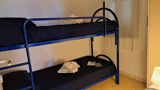 Letti a castello con lenzuola bianche.