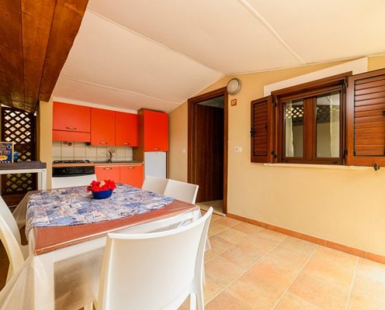 Cucina con mobili rossi, tavolo apparecchiato.