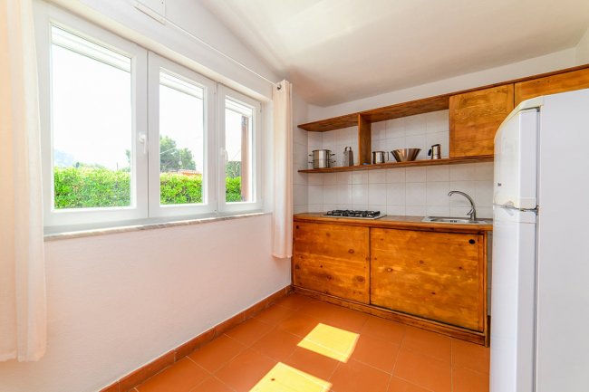 Cucina luminosa con mobili in legno e finestra grande.