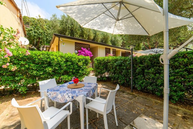 Area esterna con tavolo, sedie e ombrellone.