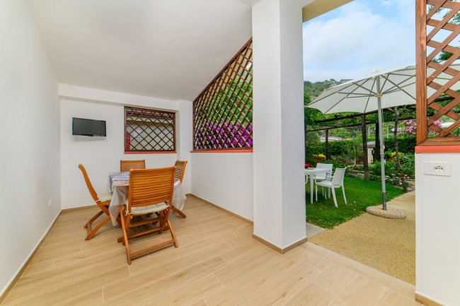 Veranda con tavolo, sedie e vista sul giardino.