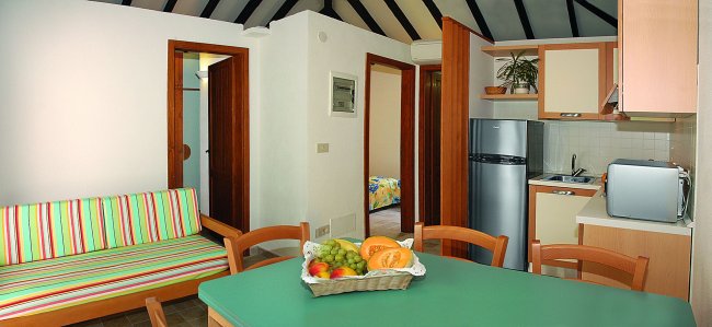 Cucina moderna con tavolo verde e frutta sul tavolo.