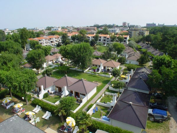 Vista aerea di villette con giardini e ombrelloni.