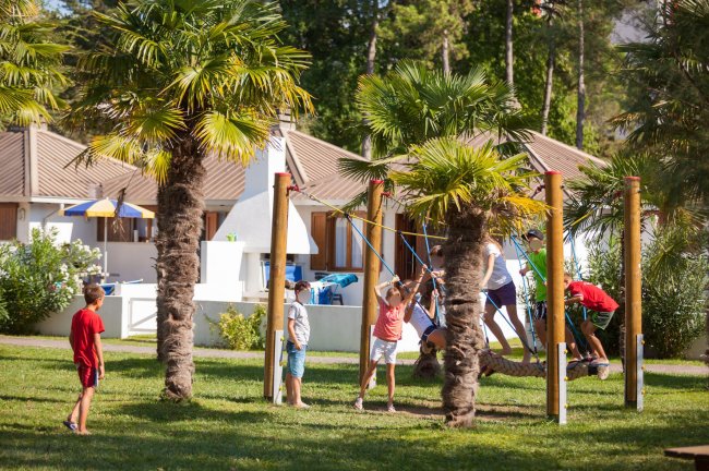 Bambini giocano su una struttura con corde in un parco.
