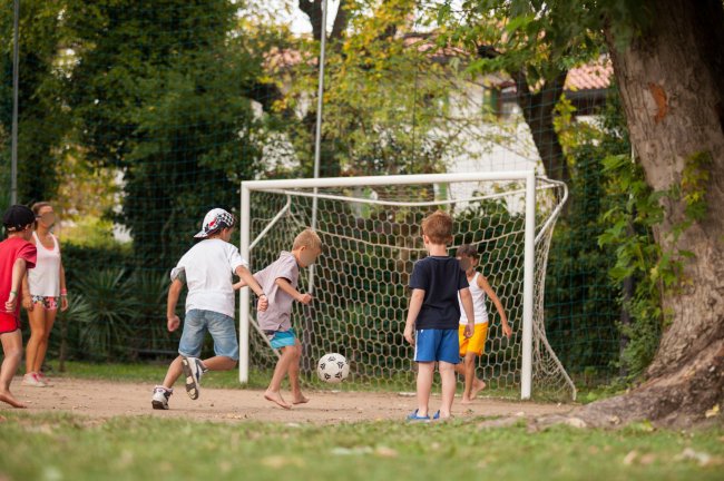 Bambini giocano a calcio vicino a una porta.