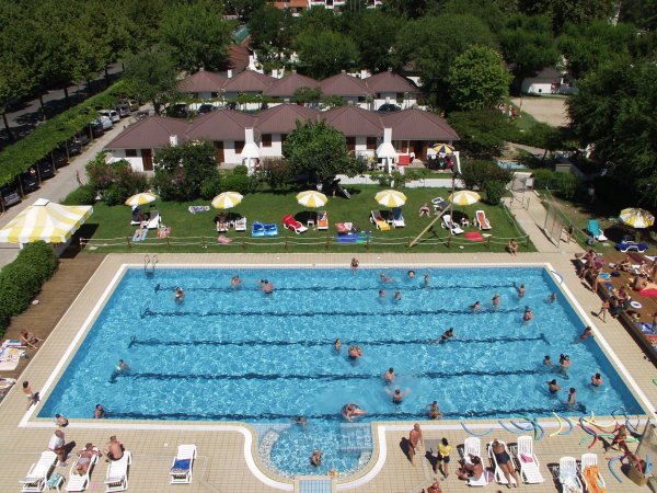 Una piscina con persone che nuotano e prendono il sole.