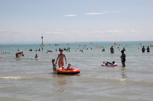 Famiglie che giocano in mare con gonfiabili colorati.