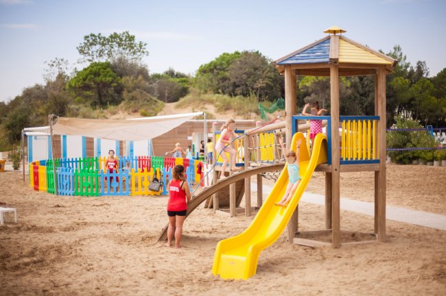 Bambini che giocano su uno scivolo in spiaggia.