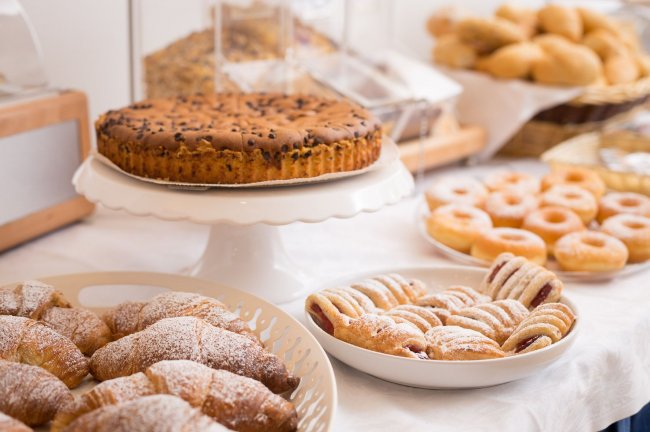 Dolci assortiti su un tavolo, inclusi ciambelle e torte.