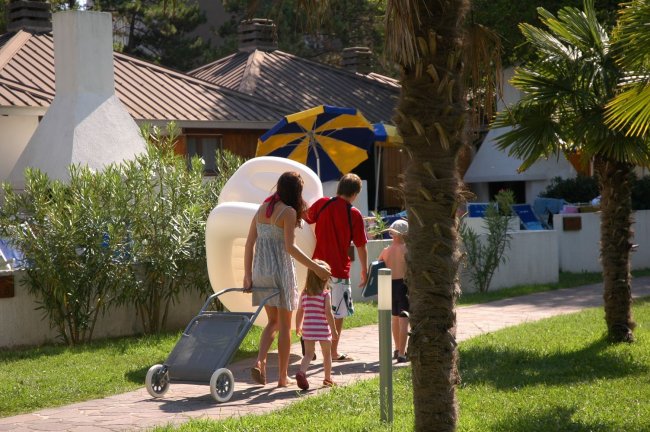 Famiglia cammina su un vialetto con attrezzature da spiaggia.