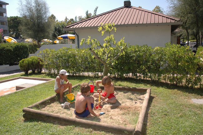 Bambini giocano in una sabbiera all'aperto.