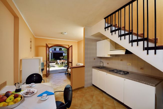 Cucina e sala con tavolo, vista su giardino esterno.