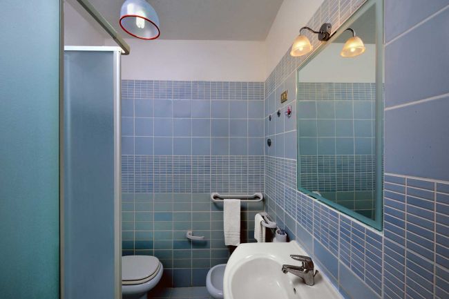 Un bagno moderno con piastrelle blu, doccia e lavandino.