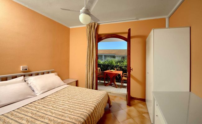 Camera da letto con balcone e tavolo esterno.