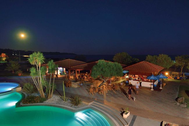 Piscina illuminata di notte, con luna sullo sfondo.