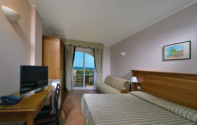 Camera con letto matrimoniale, TV e balcone vista mare.