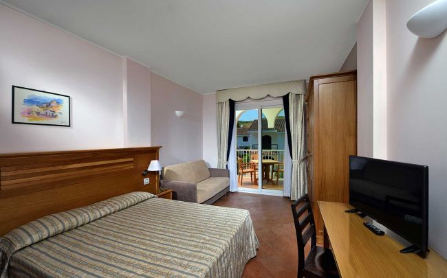 Camera con letto matrimoniale, TV e balcone vista cortile.