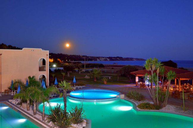Piscina illuminata al tramonto, vista mare.