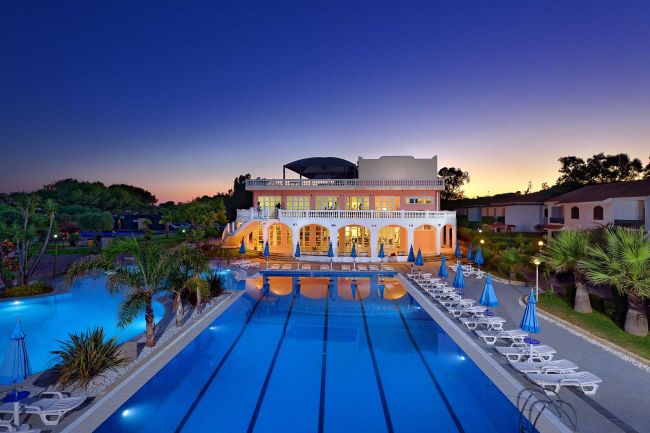 Edificio illuminato con piscina al tramonto.