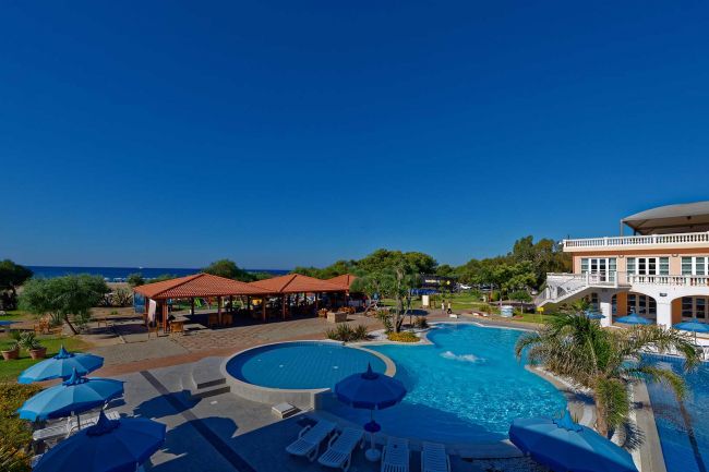 Piscina con ombrelloni blu e vista sul mare.