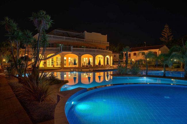 Piscina illuminata di notte, edificio con archi.