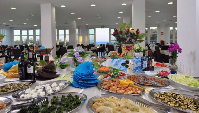 Tavolo buffet con cibo e decorazioni floreali.