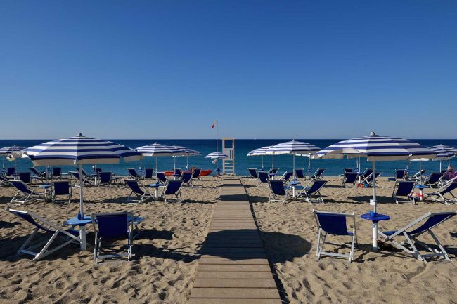 Spiaggia con ombrelloni a righe blu e bianche.