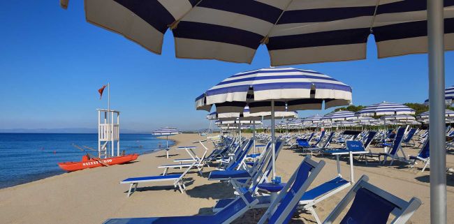 Spiaggia con ombrelloni a strisce blu e bianche.