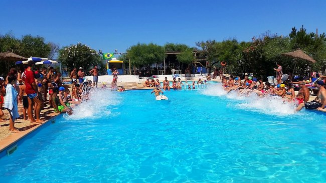 Piscina affollata con persone che si divertono e spruzzi d'acqua.