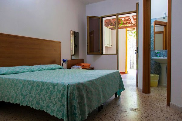 Camera da letto semplice con bagno e finestra aperta.