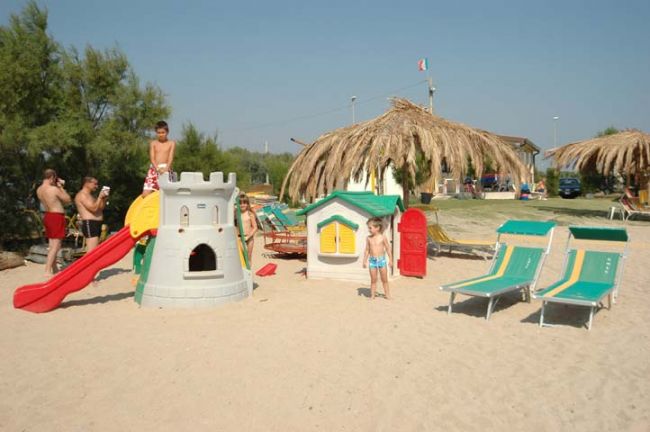 Area giochi in spiaggia con sdraio e scivolo.
