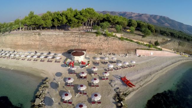 Spiaggia con ombrelloni bianchi, sdraio e canoe arancioni.