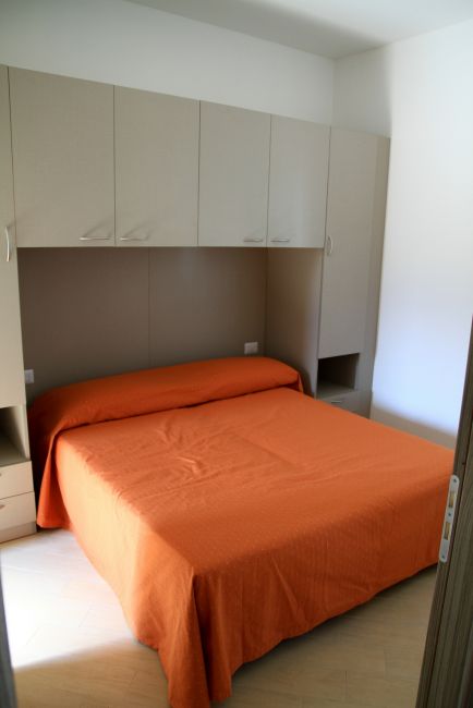 Camera con letto matrimoniale e copriletto arancione.