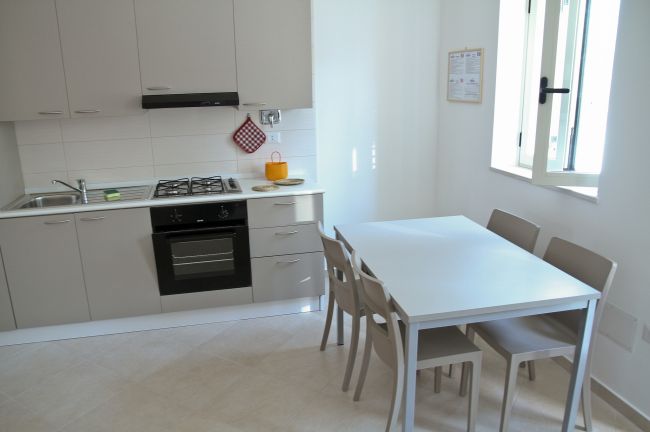 Cucina moderna con tavolo e sedie beige.