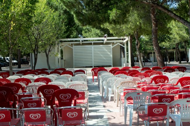 Sedie rosse e bianche all'aperto con palco.