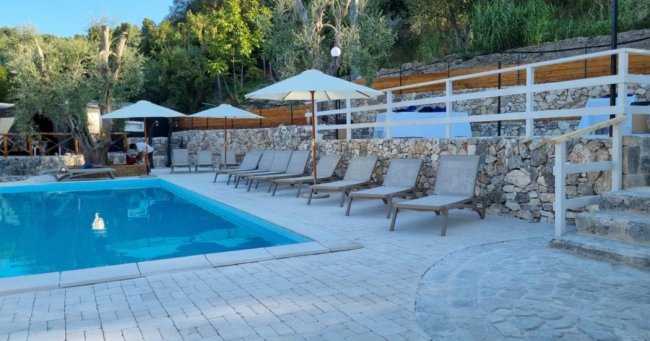 Piscina con sedie a sdraio e gradini in pietra.