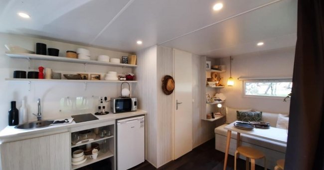 Cucina compatta con mensole aperte, tavolo da pranzo.