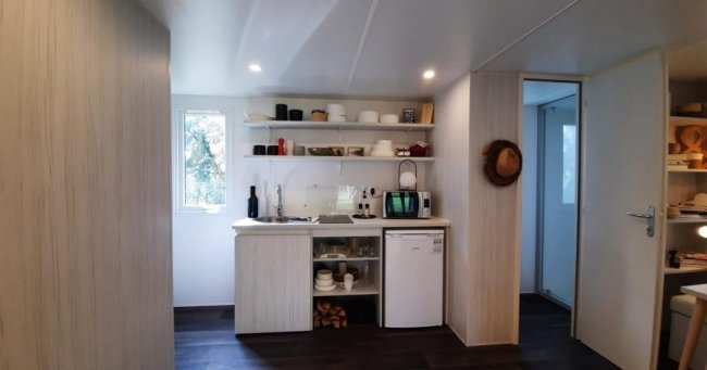 Cucina piccola con mensole e mini-frigo.