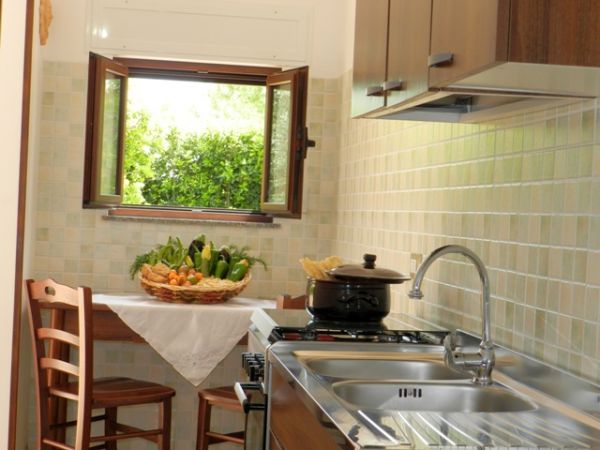 Cucina con finestra aperta, verdure sul tavolo.