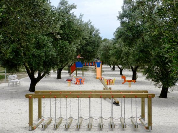 Area giochi all'aperto con altalene tra alberi.