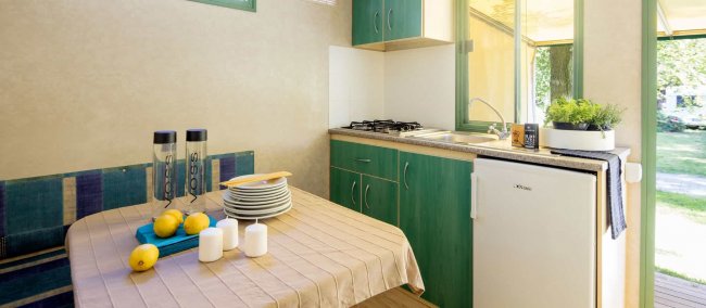 Interno di una roulotte con cucina e tavolo apparecchiato.