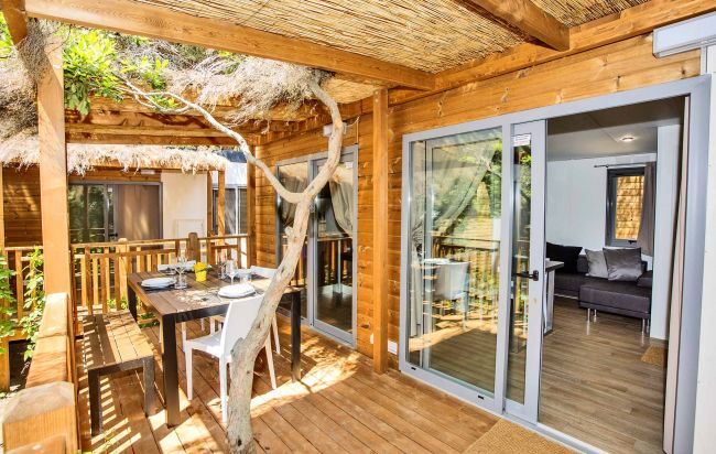 Terrazza coperta con tavolo e sedie accanto ad alberi.