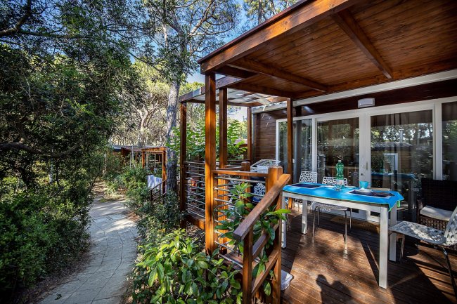 Veranda in legno con tavolo e sedie in un giardino.