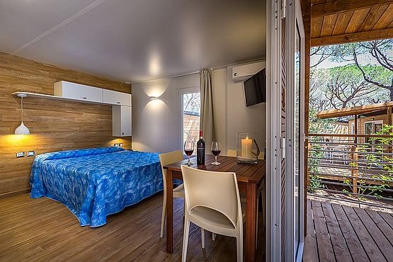 Interno con letto blu, tavolo e sedie.