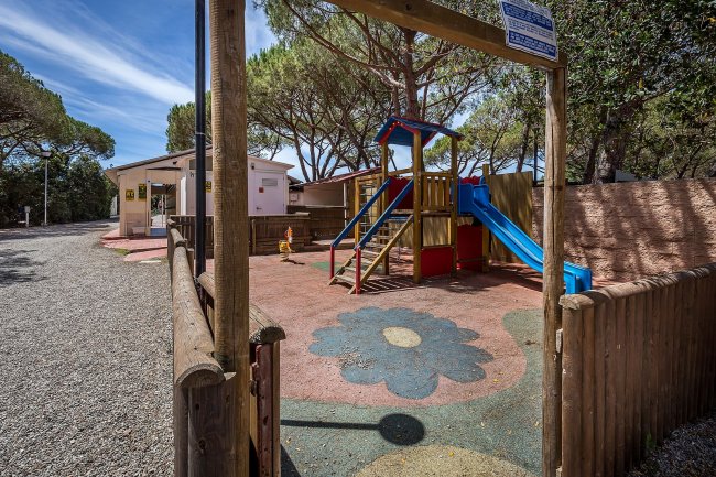 Area giochi all'aperto con scivolo e pavimento colorato a forma di fiore.