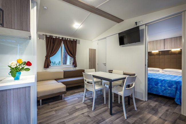 Soggiorno con divano beige, tavolo e sedie bianche.