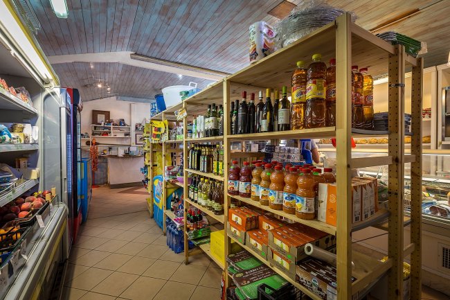 Un piccolo supermercato con scaffali di bevande, vino e alimenti vari.