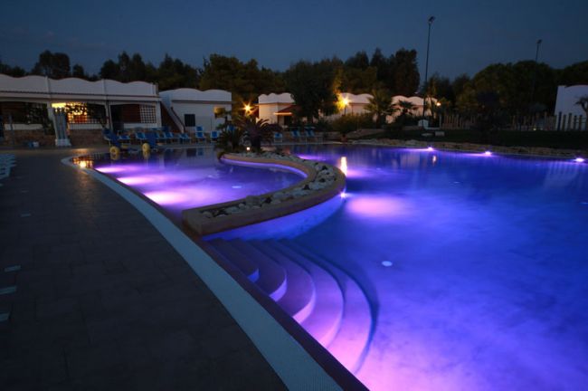 Piscina illuminata di viola di notte, con gradini sott'acqua.